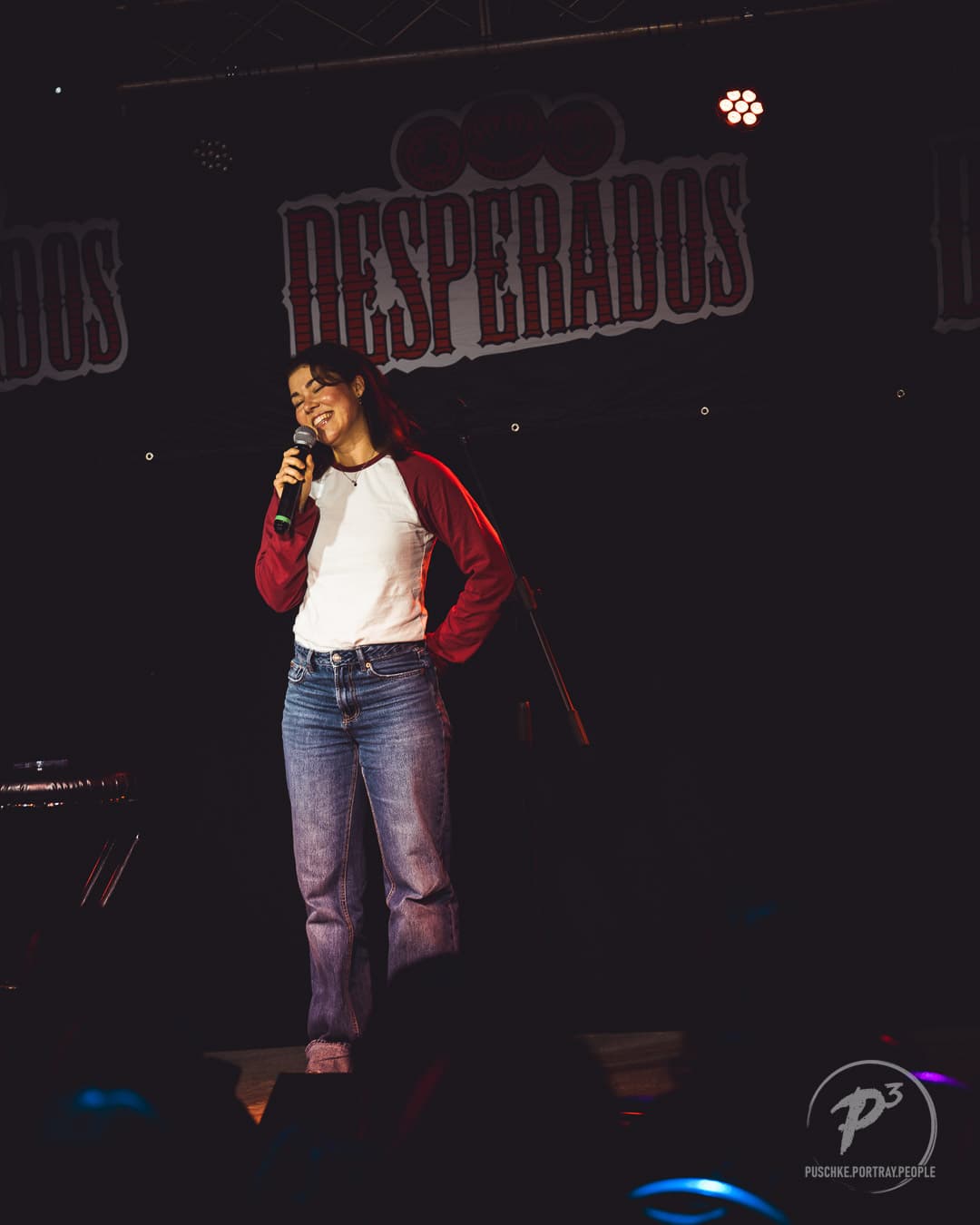 Comedienne mit Mikrofon auf der Bühne bei BuxteComedy